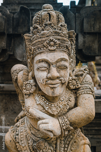 A close up on a guardian figure next to Pura Tirta Empul temple on Bali. Traditional and historical site. Sculpture of a Balinese temple guardian © irengorbacheva