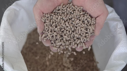 Granule feed for rural animals falls from the hands of a male farmer. Slow motion photo