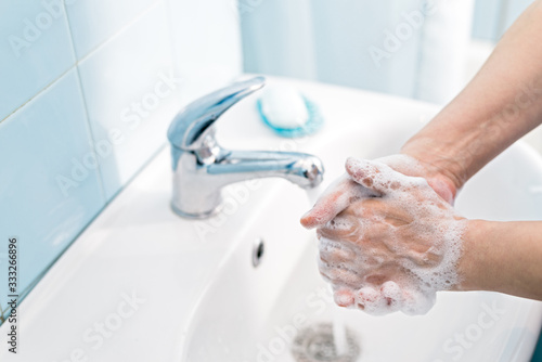 Woman washing hands with soap under the water tap