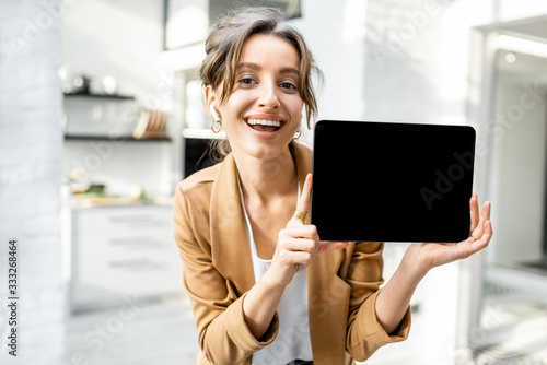 Well-dressed cheerful business woman with a digital tablet indoors, showing tablet with a black screen to copy paste