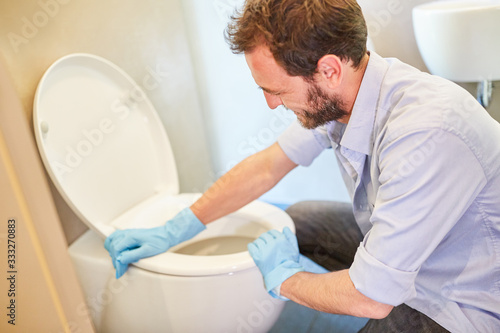 Houseman as a cleaning man at the toilet or toilet clean