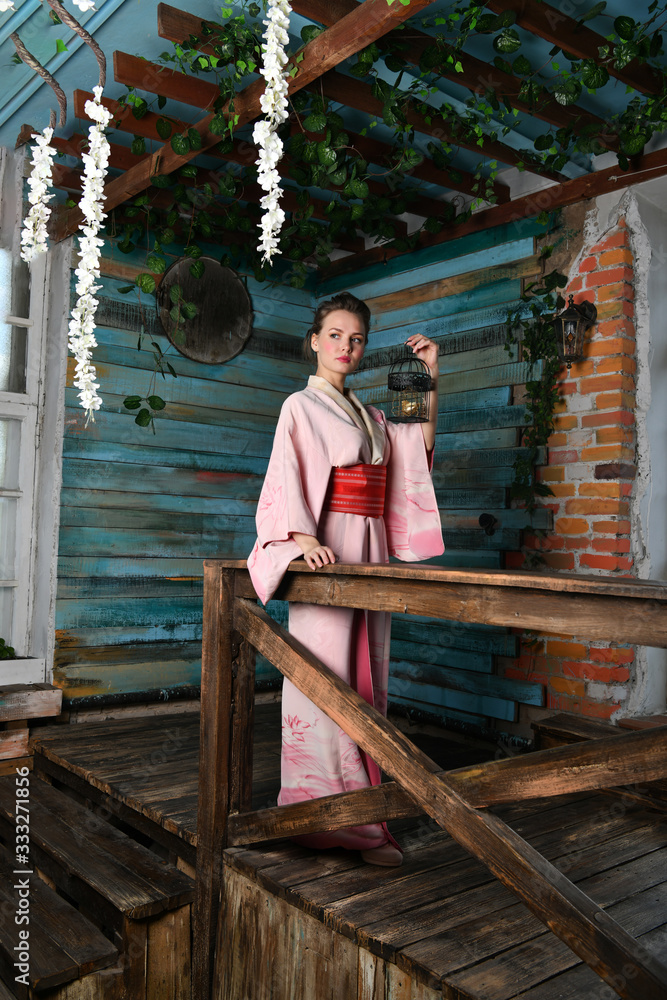 beautiful girl in a pink kimono with a cage with a bird