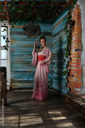 beautiful girl in a pink kimono with a cage with a bird