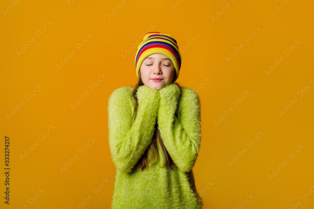 © Tina kids photo - Happy teen girl in green sweater and multi-colored knitted hat on a yellow background © Tina kids photo - Happy teen girl in green sweater and multi-colored knitted hat on a yellow background