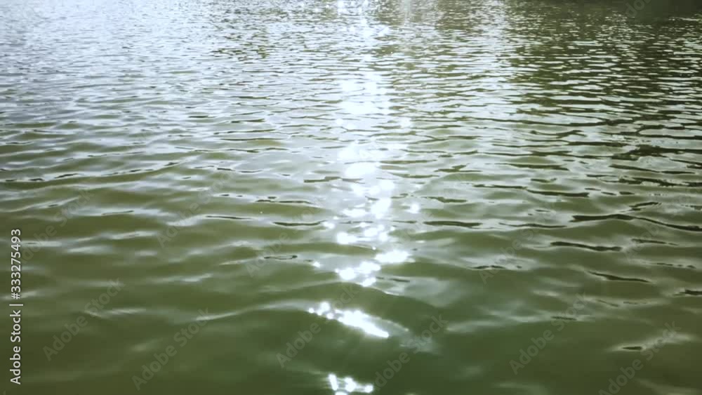 Glare of sunlight on the surface of the water in the lake. Reflection of light on the waves of the city lake Glare of sunlight on the surface of the water in the lake. Reflection of light on the waves of the city lake