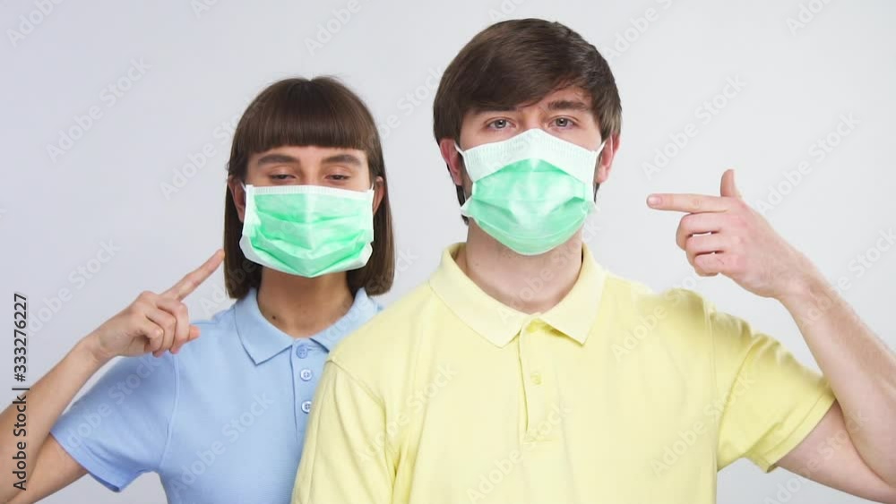 young couple in protection sterile masks pointing on face with facial protector young couple in protection sterile masks pointing on face with facial protector