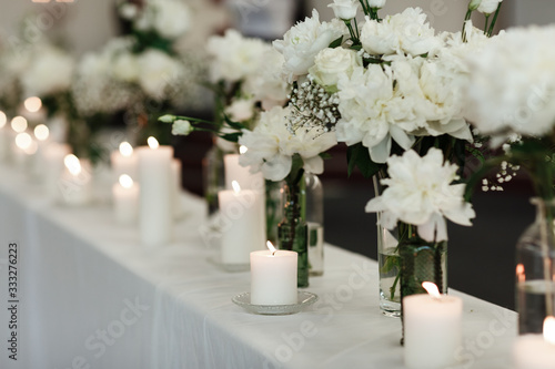 Table setting at wedding reception. Floral compositions with beautiful flowers and greenery, candles on decorated table. Coziness and style. Modern event design. selective focus.