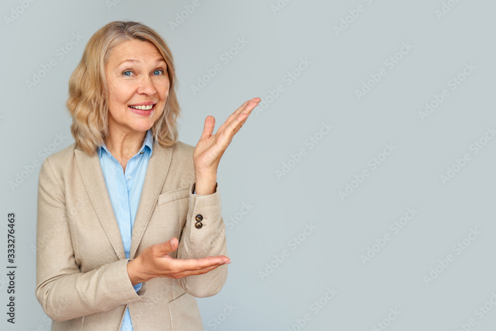 © JENOCHE - Portrait of business woman pointing up and looking at the camera over gray background .
