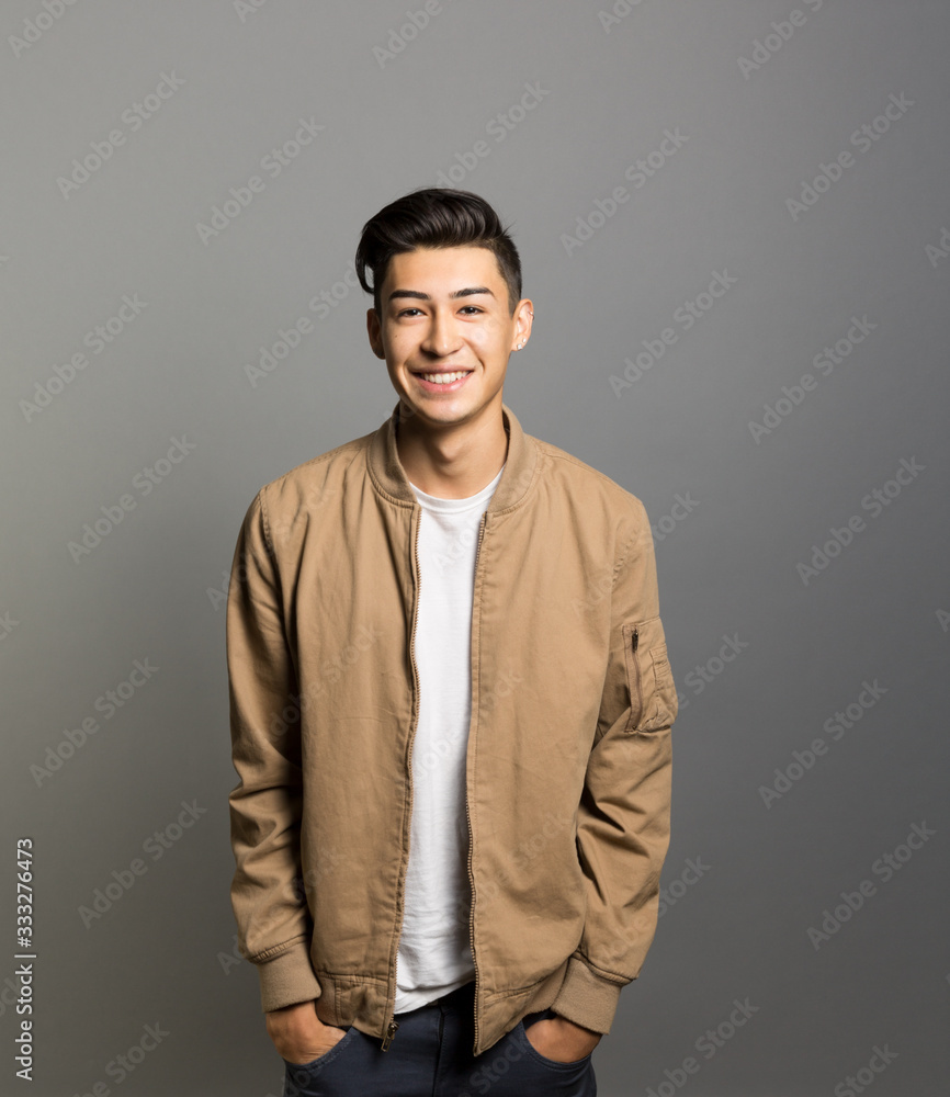 Obraz premium Portrait of smiling young man standing against gray background