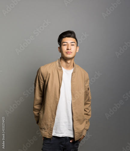 Portrait of young man standing against gray background