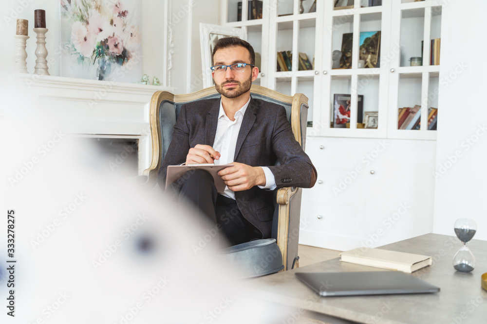 Fototapeta premium Dark-haired modern entrepreneur relaxing in an armchair