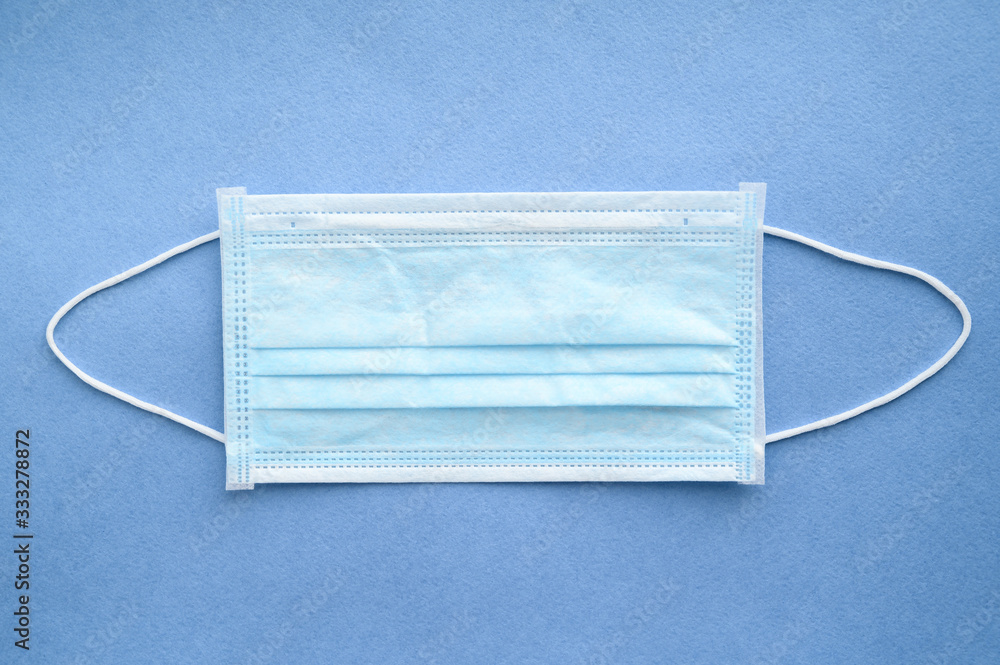 Medical surgical mask on a blue background. Face mask to protect the mouth and nose. Top view. Coronavirus protection concept.