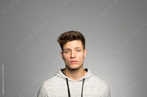 Portrait of young man standing against gray background