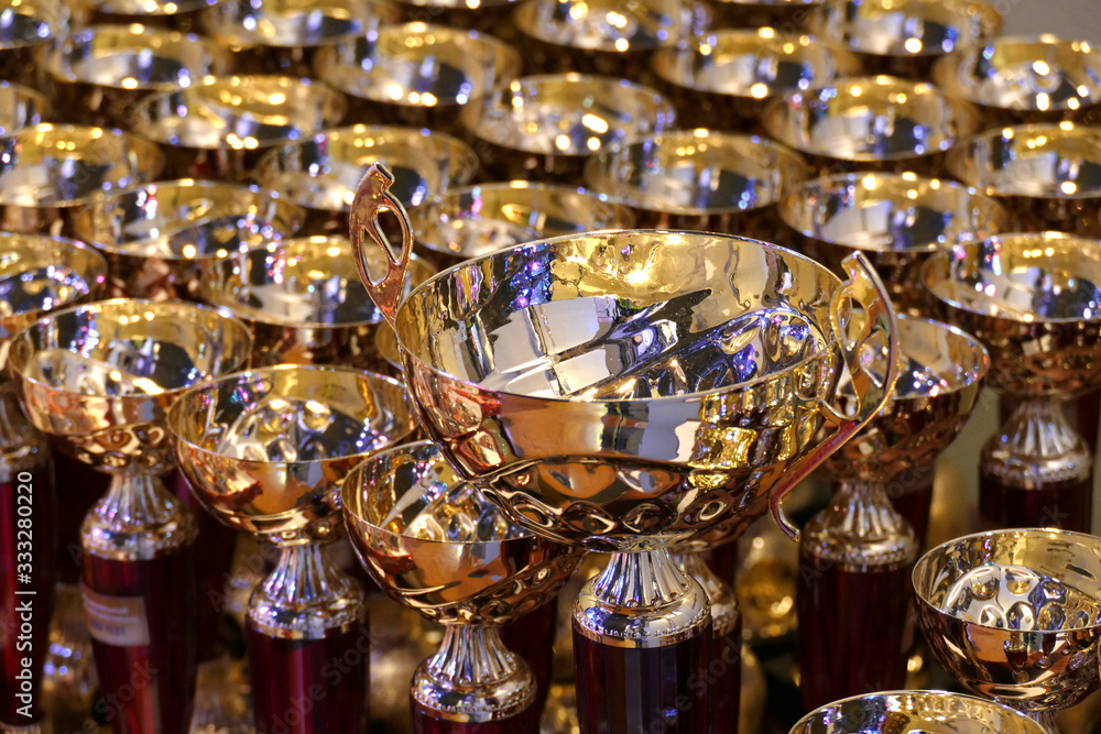 beautiful gold cup on a background of cups for awarding. many beautiful gold cups for rewarding, gold cups for winners, collection of gilded goblets,championship award cups,award products for the comp beautiful gold cup on a background of cups for awarding. many beautiful gold cups for rewarding, gold cups for winners, collection of gilded goblets,championship award cups,award products for the comp