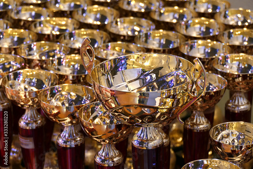 beautiful gold cup on a background of cups for awarding. many beautiful gold cups for rewarding, gold cups for winners, collection of gilded goblets,championship award cups,award products for the comp