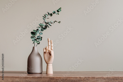 Dry eucalyptus branches in modern vase near wooden hand photo