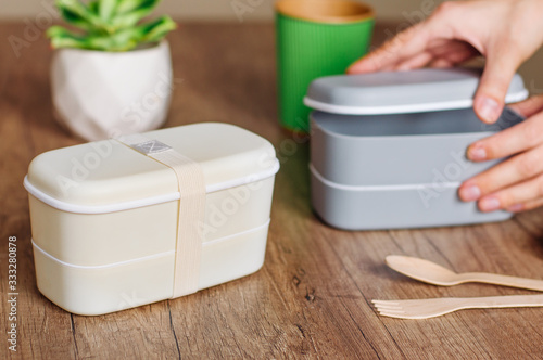 Two closed plastic two-layered lunch boxes with elastic bands on wooden table photo