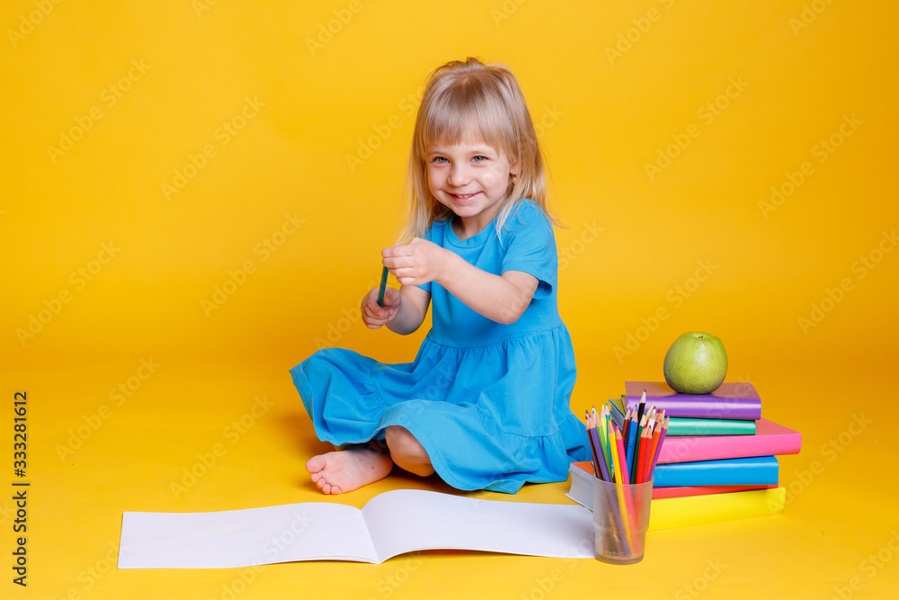child girl draws colored pencils on a yellow background. Concept of preschool education child girl draws colored pencils on a yellow background. Concept of preschool education