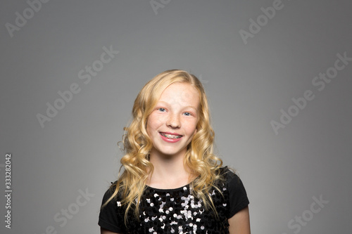 Portrait of teenage girl standing against gray background