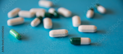 Set of white and colored pills on a blue background. Blur. Close up