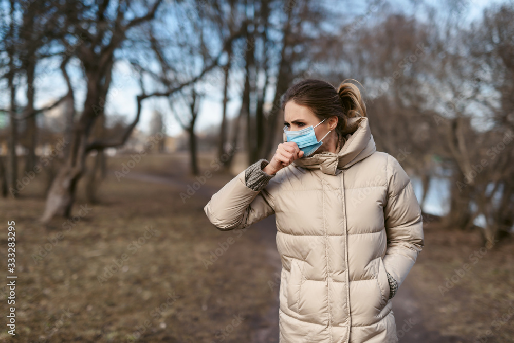 Prevention of coronavirus outbreak in 2020. Outdoor portrait of young european woman wearing a disposable facial mask. Prevent pollution and disease concept.