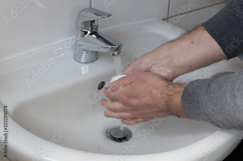 Detail of a Young male washing his Hands with Soap under running water in order to reduce infection Risk during corona Virus pandemic