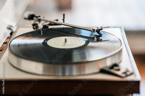 vinyl record turntable on wooden base playing a vinyl record