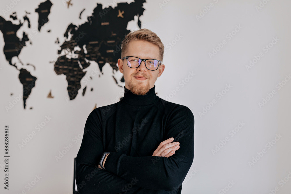 Handsome male manager looking at camera and smiling while sitting in the modern light office. Handsome male manager looking at camera and smiling while sitting in the modern light office.