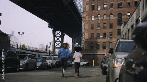 Joggers running outside in New York City with skyline and Brooklyn Bridge in background