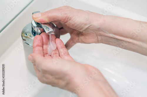 Woman hand pump soap in order to kill germs and prevent covid-19