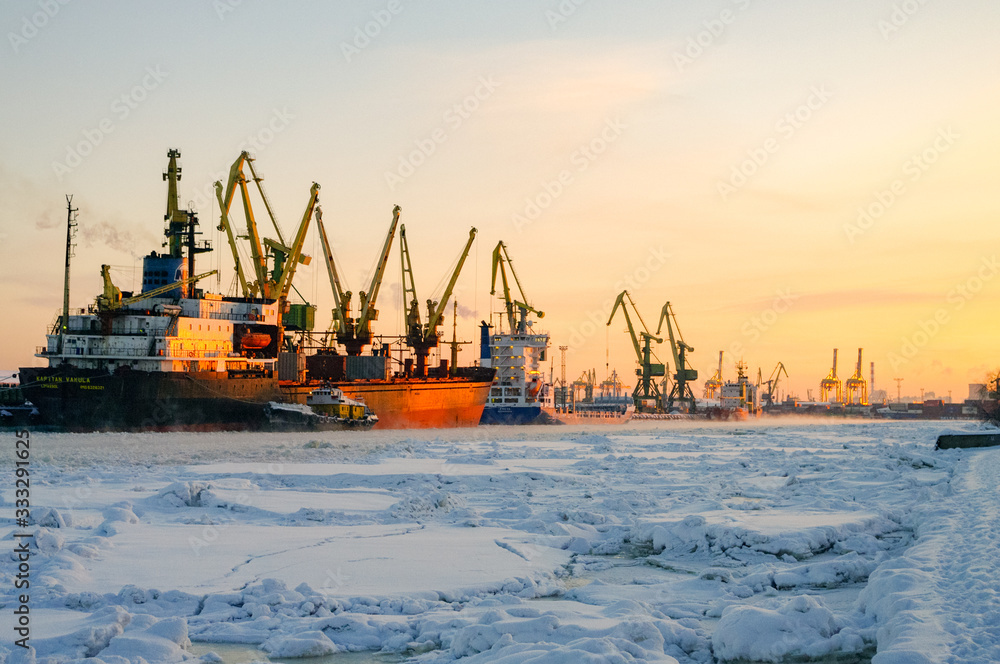 Fototapeta premium Statki i dźwigi w porcie towarowym St. Petersburg w okresie zimowym, pokryte lodem i śniegiem
