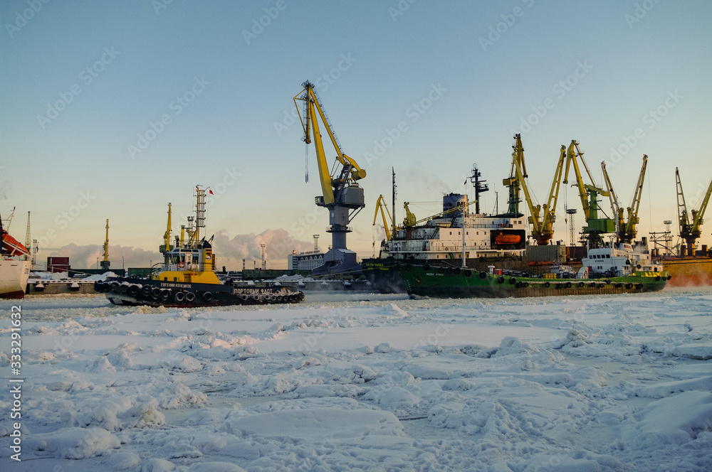 Ships and cranes in cargo port of St. Petersburg in winter time, covered by ice and snow Ships and cranes in cargo port of St. Petersburg in winter time, covered by ice and snow