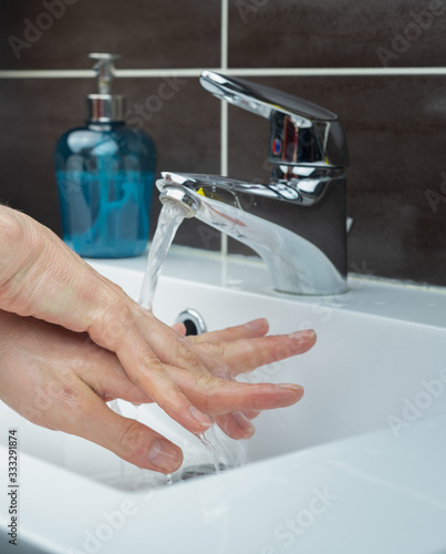 Doctor nurse cleaning and sanitizing or desinfecting hands with hand sanitizer or soup because of Coronavrius Covid-19 photo