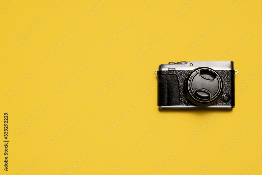 Vintage retro mirrorless camera with lens and lens cap shot from above on a yellow background