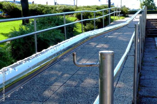 Foto sloped concrete handicap access ramp with stainless steel handrail and guard rail
