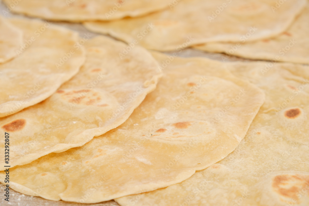 Stack of homemade whole wheat flour tortilla on wooden table Stack of homemade whole wheat flour tortilla on wooden table