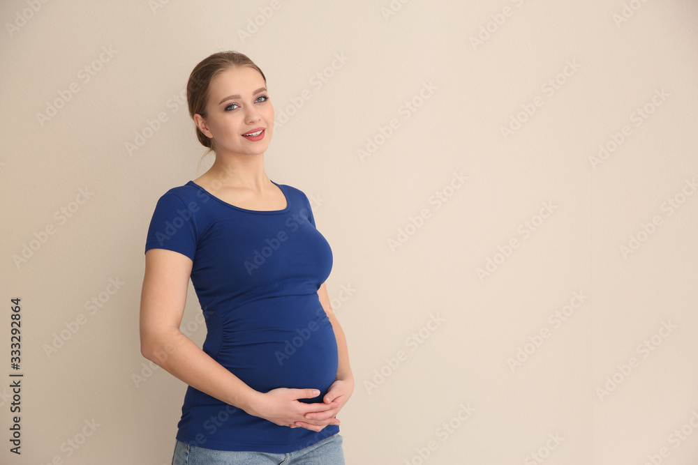 Young pregnant woman on beige background. Space for text Young pregnant woman on beige background. Space for text