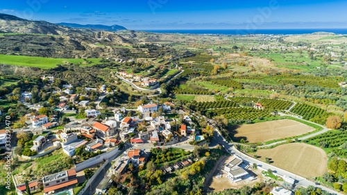 Aerial bird's eye view of Goudi village in Polis Chrysochous valley, Paphos, Cyprus. View of traditional ceramic tile roof houses, church, trees, hills and Akamas - Latchi beach bay from above.