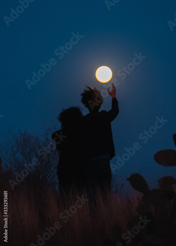 Obraz na płótnie Pareja abrazándose al anochecer frente a la luna
