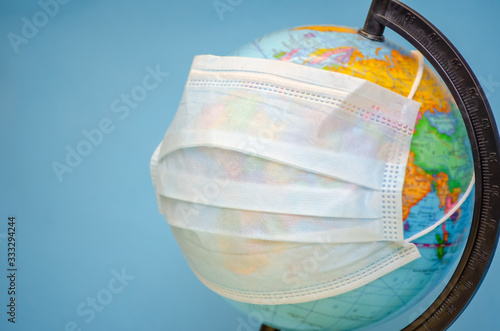 Globe with a medical mask close-up on a blue background with a copy of the space. concept of the coronavirus  infectious diseases