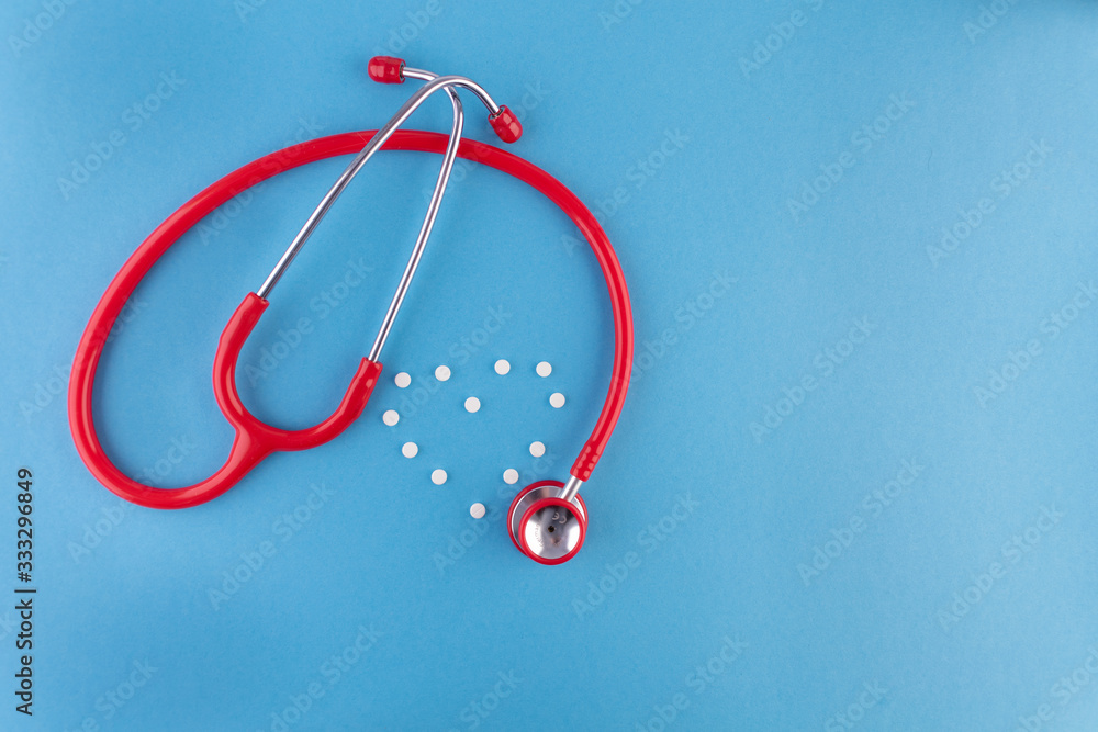 Close up isolated of red stethoscope with pills in heart shape on light blue background with a place for text. Medical mockup or template. Close up isolated of red stethoscope with pills in heart shape on light blue background with a place for text. Medical mockup or template.