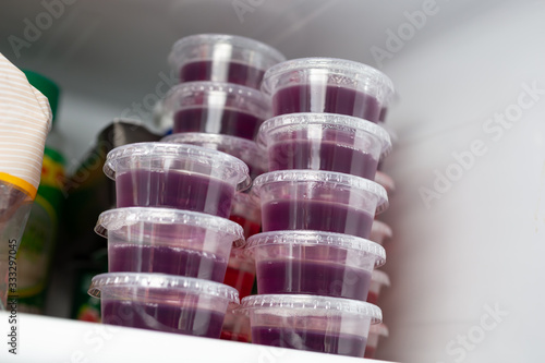 Obraz na plátně A view of several condiment cups full of grape flavored gelatin shots, on display inside a home refrigerator