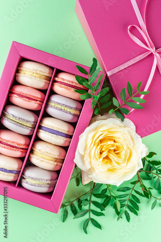 Colorful macaroons and flowers. Sweet macarons in gift box. Top view