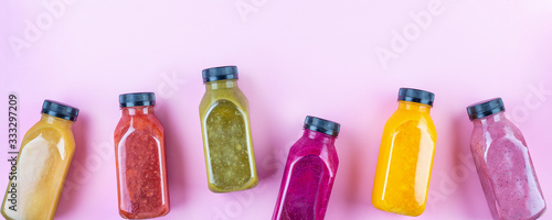 Colourful healthy smoothies and juices in bottles on color background with copy space.