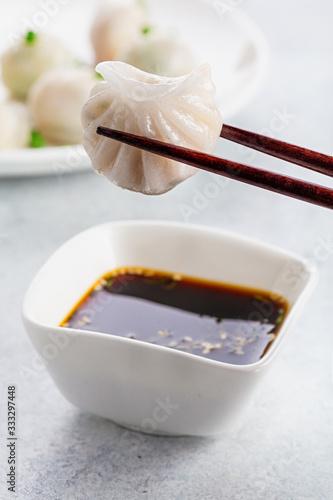 Dumpling being dipped in soy sauce with chopsticks