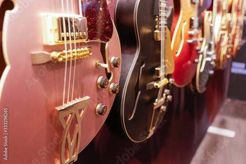 A closeup view of several archtop guitars hanging on the wall of a music store.