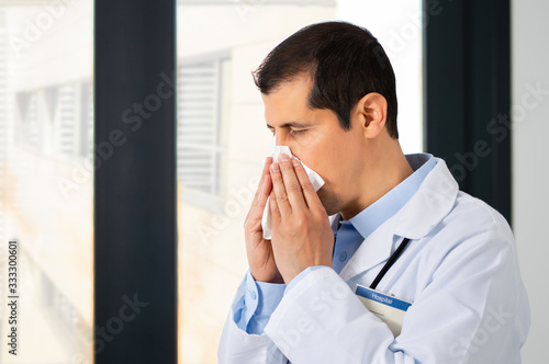 Shot of a male doctor blowing his nose in an hospital