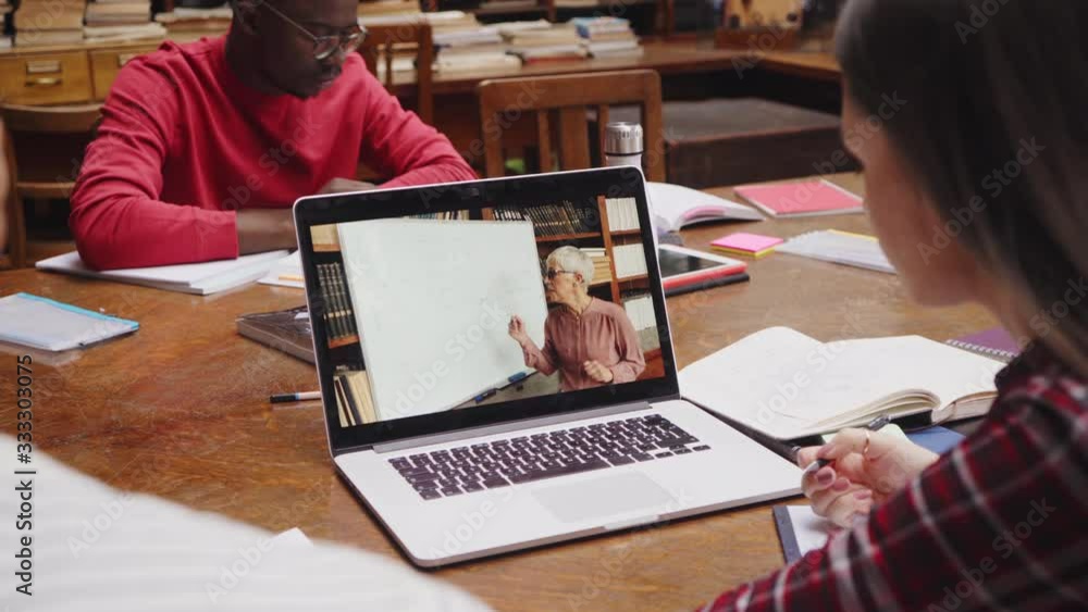Video Call Lesson Teacher explaining lesson in video call while girl taking notes. Rear ...