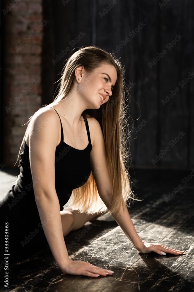 Naklejka premium Close-up Athletic girl in sports wear sits on a split. Gymnast does stretching before exercise at the morning