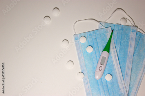 Medical masks and thermometer and tablets on white background with free space for text